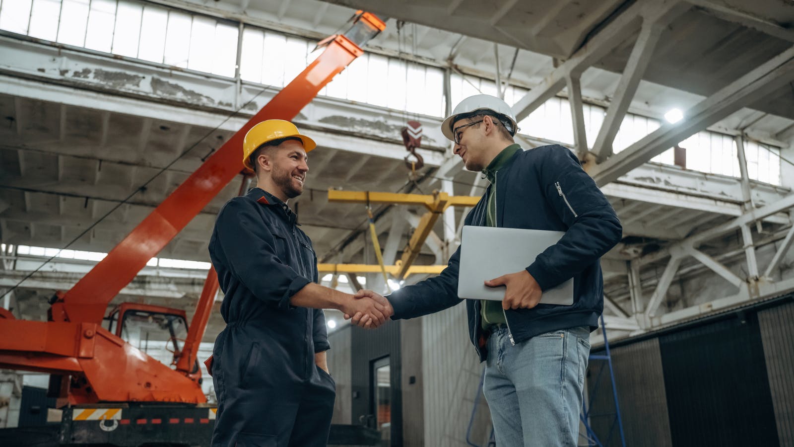 Two male workers in a factory shaking hands.