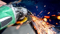 A worker uses an angle grinder, an industrial abrasives product. A worker uses an angle grinder, an industrial abrasives product.