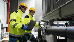 Two technicians repair a pipe in a factory