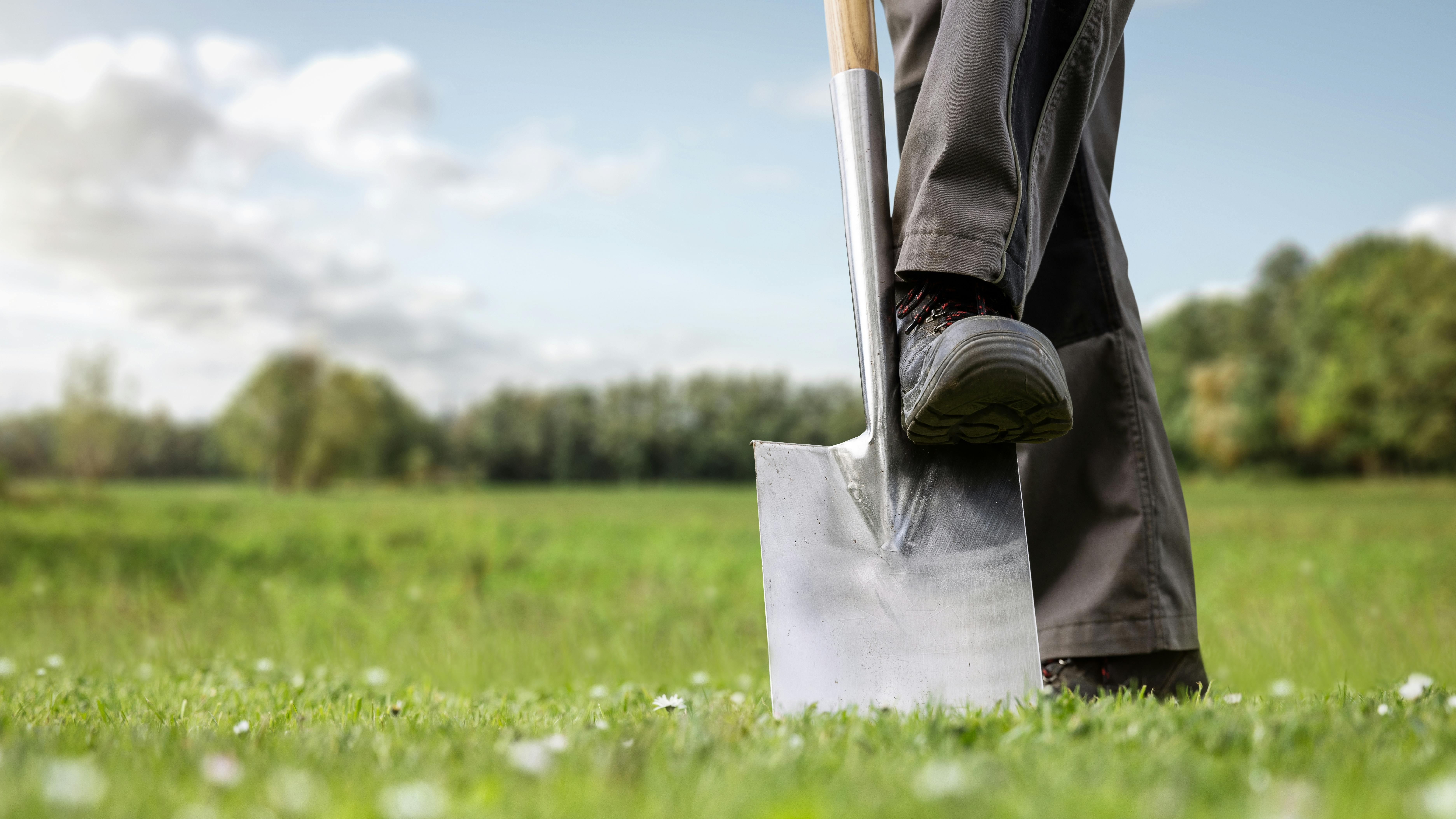 A man driving a shovel into grassy ground