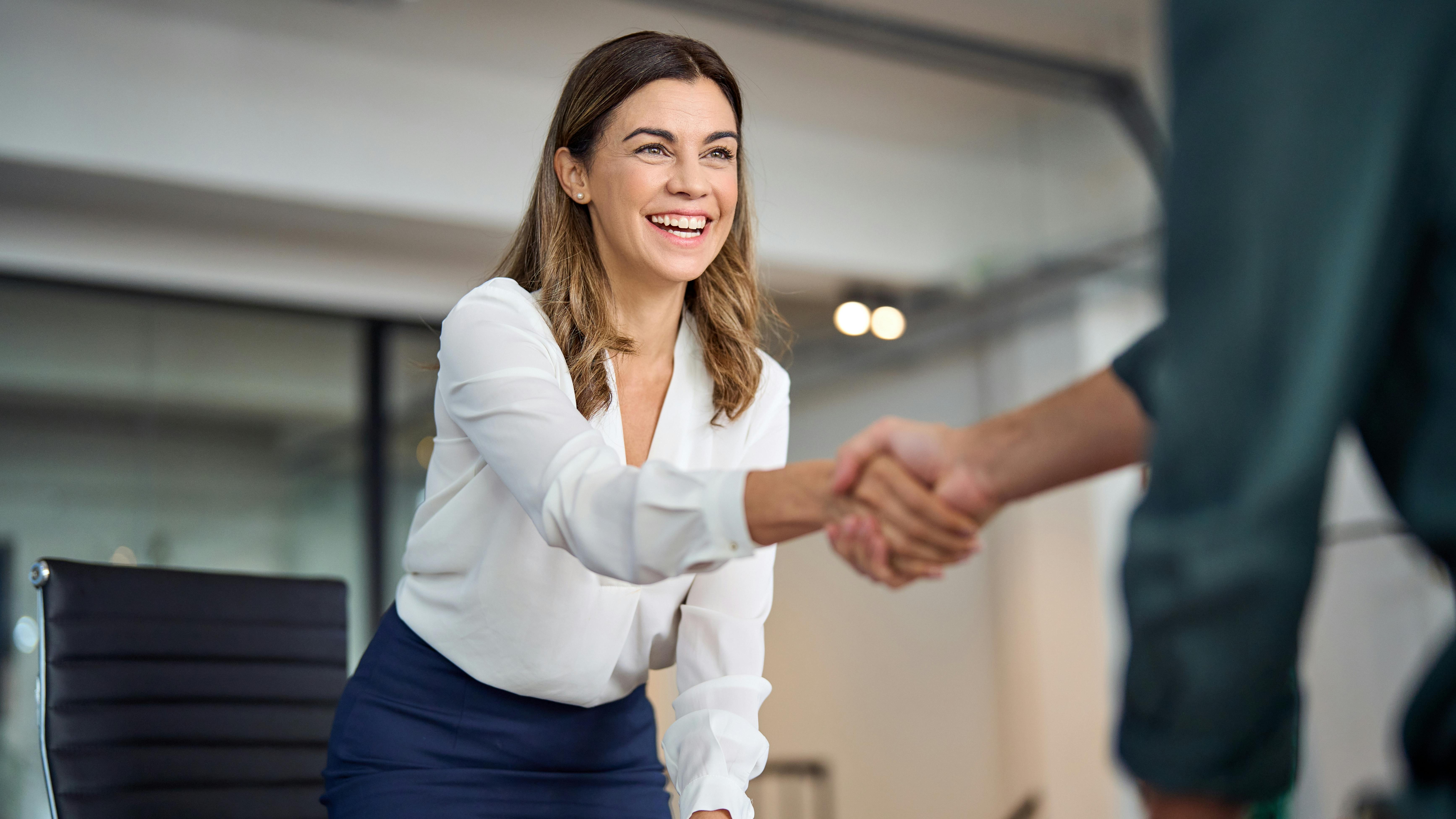 A businesswoman shakes hands with a businessman