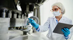 A process technician examines pharmaceutical manufacturing equipment
