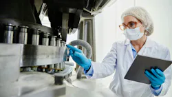 A process technician examines pharmaceutical manufacturing equipment